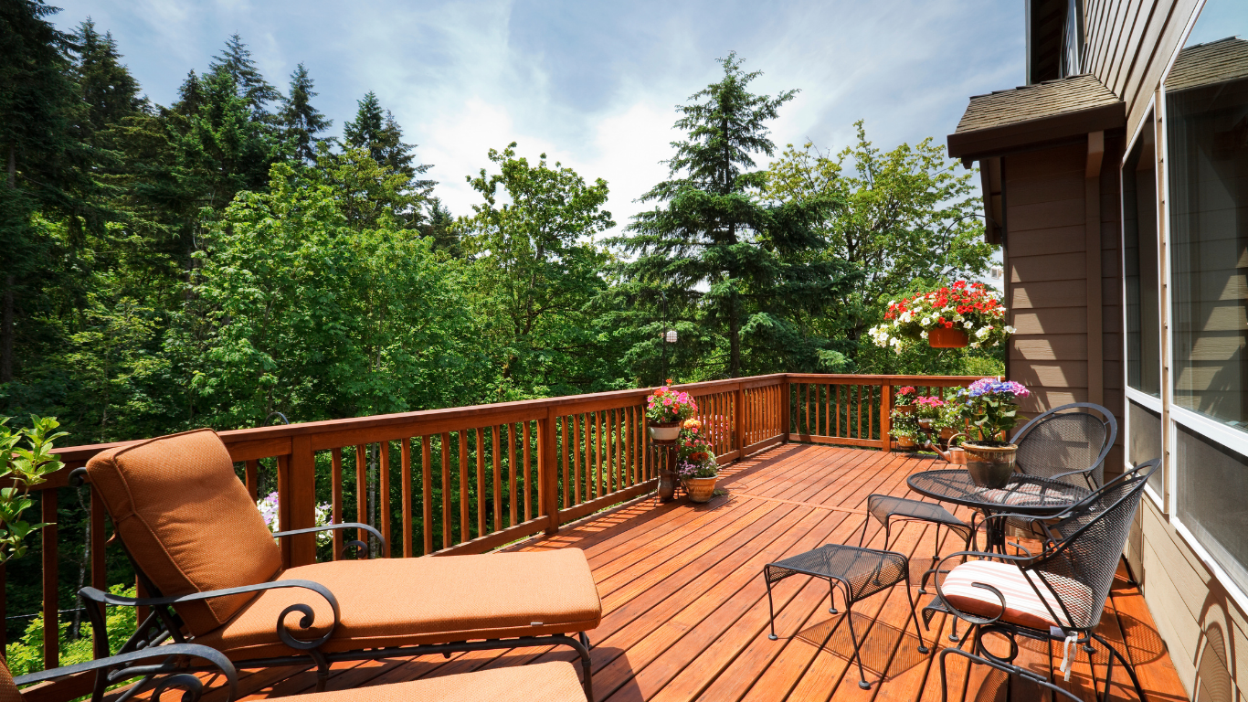 Wooden deck with lounge chairs and table overlooking lush green trees and a forested view