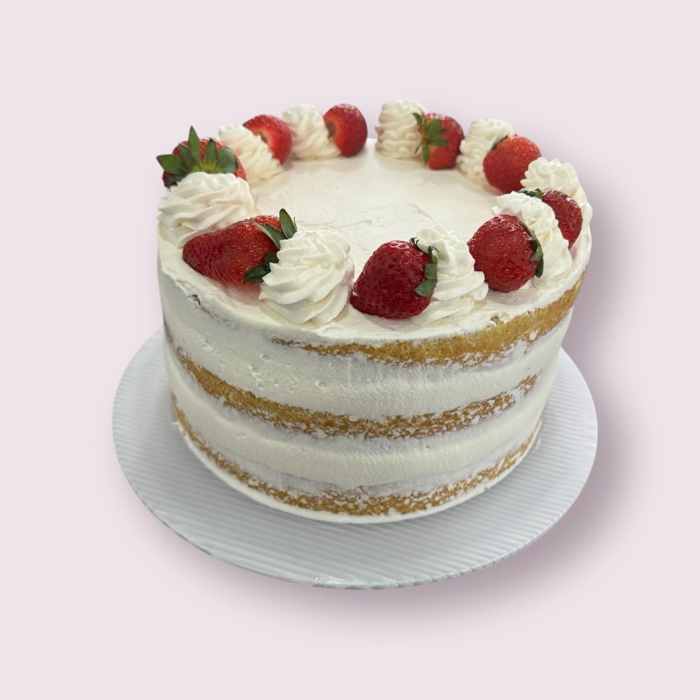 Strawberry shortcake with visible layers, white frosting, and strawberry garnish.