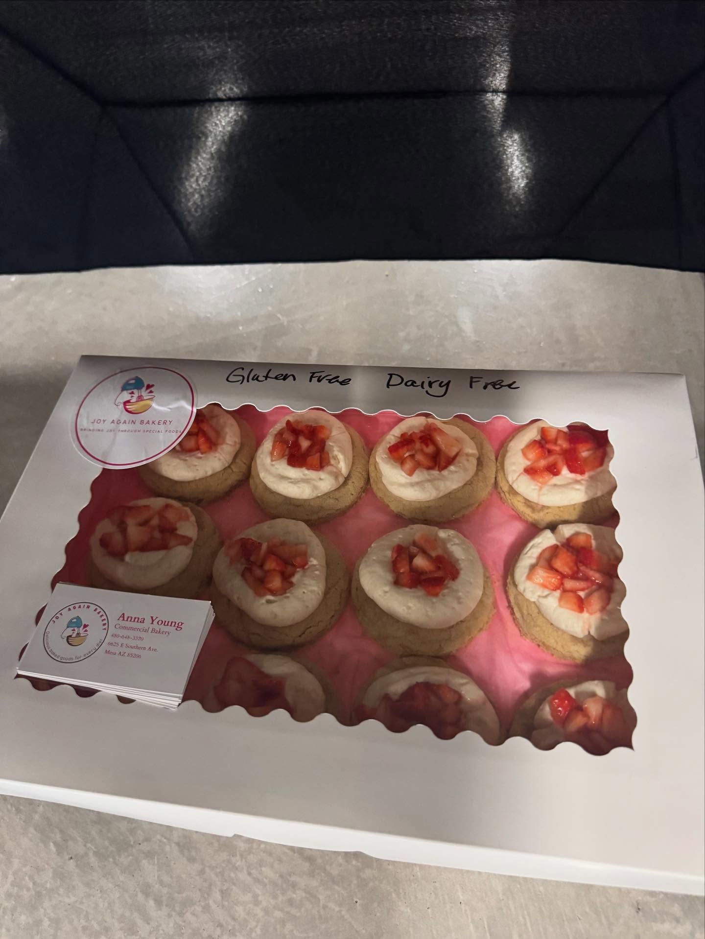 Box of strawberry cream-topped cookies, on a white surface, with a logo on the box.
