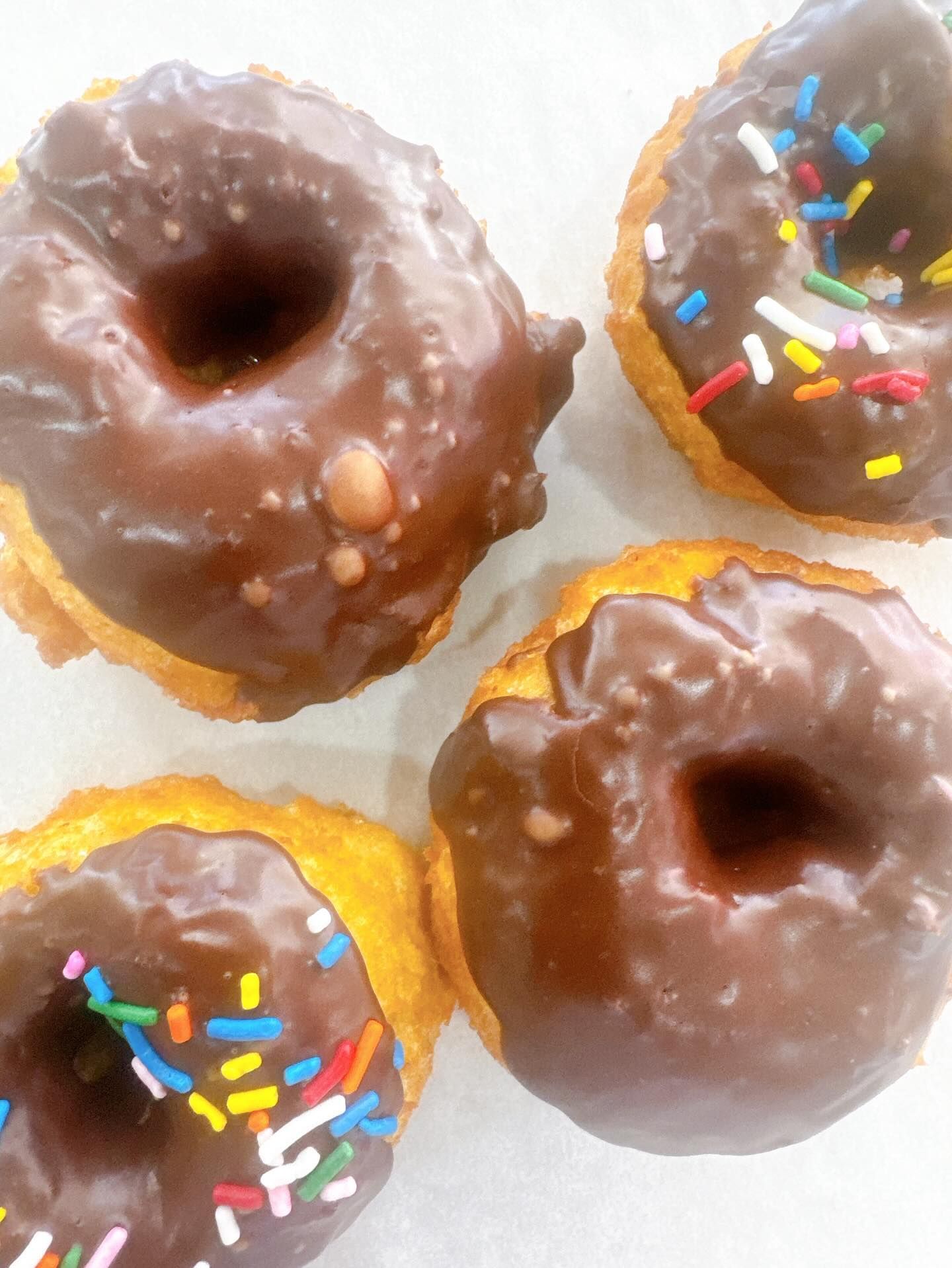 Four chocolate-frosted donuts; two with sprinkles.
