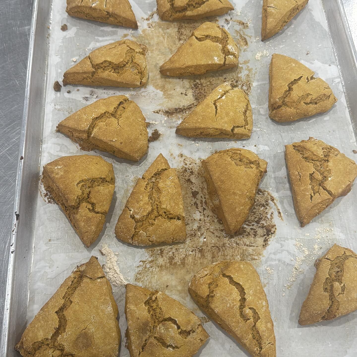 Triangular, golden-brown baked goods arranged on a baking sheet.