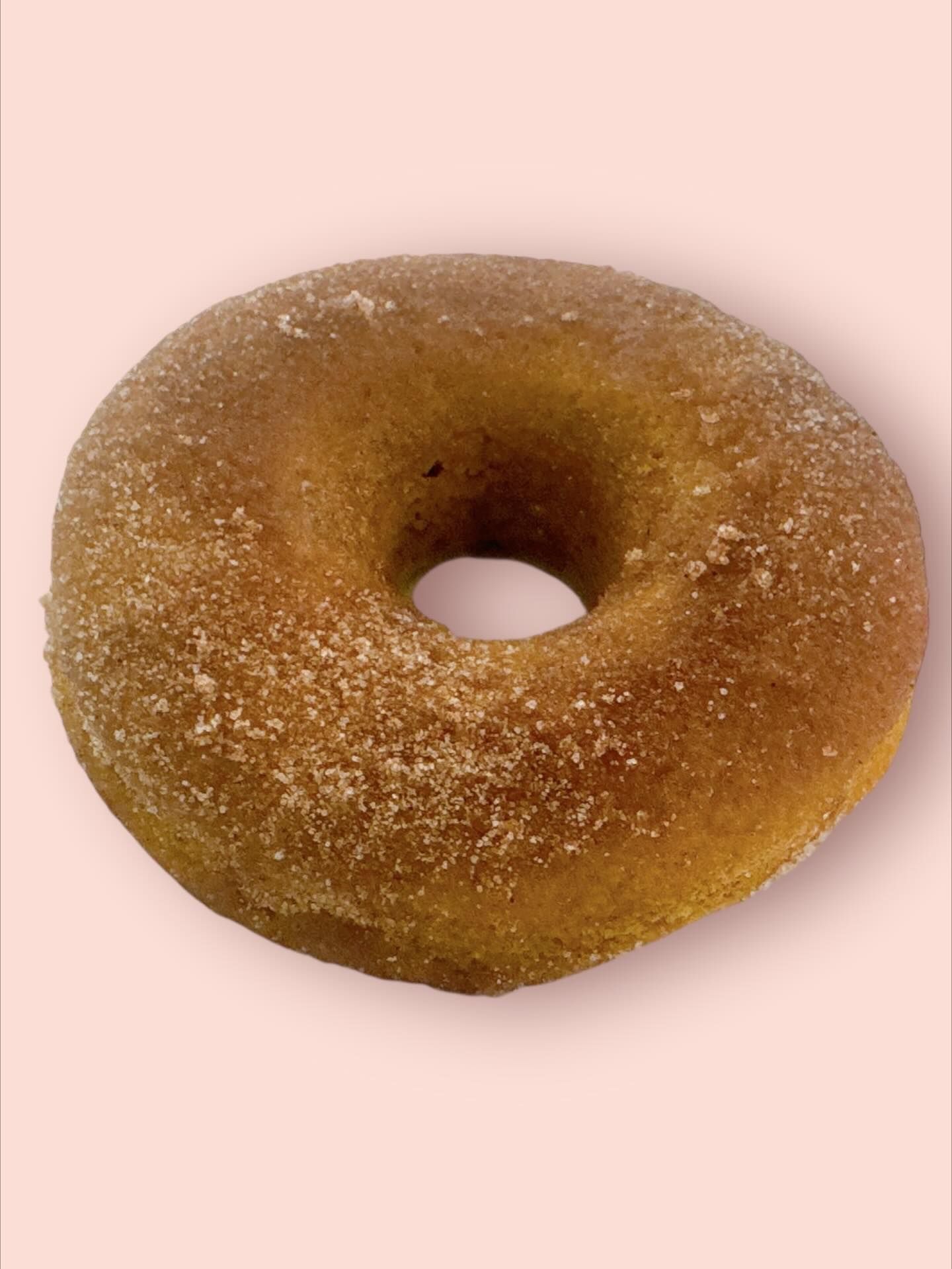 Cinnamon sugar donut on a light pink background.