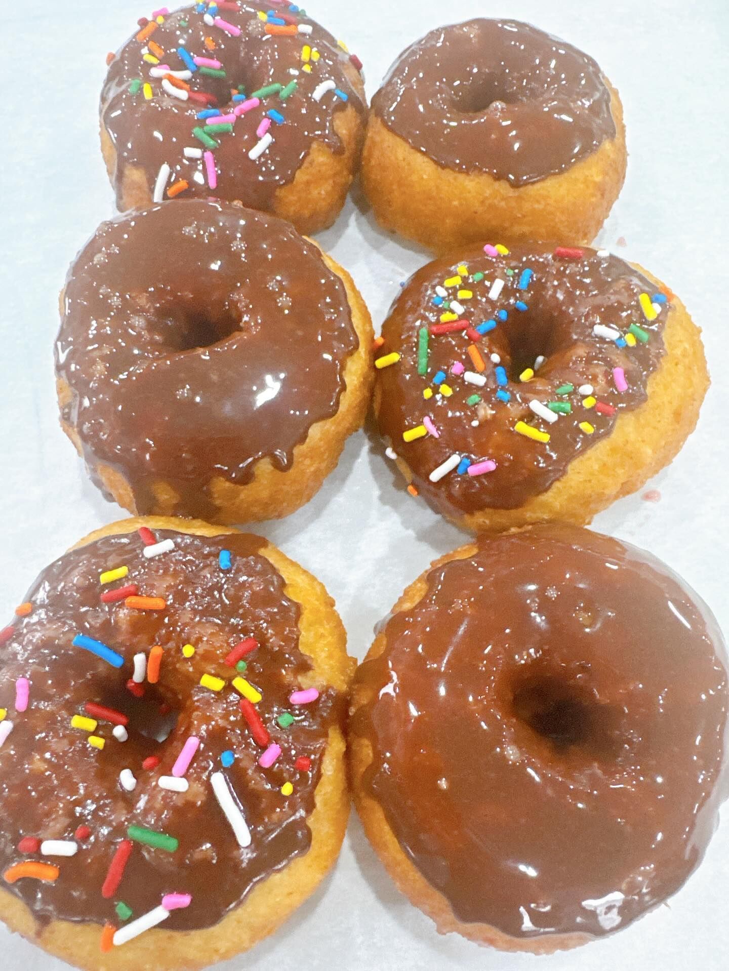 Six chocolate-frosted doughnuts, some with colorful sprinkles.