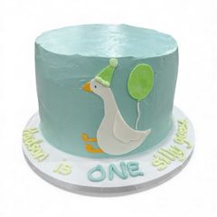 A teal frosted cake with a cartoon goose wearing a party hat, balloon, and 