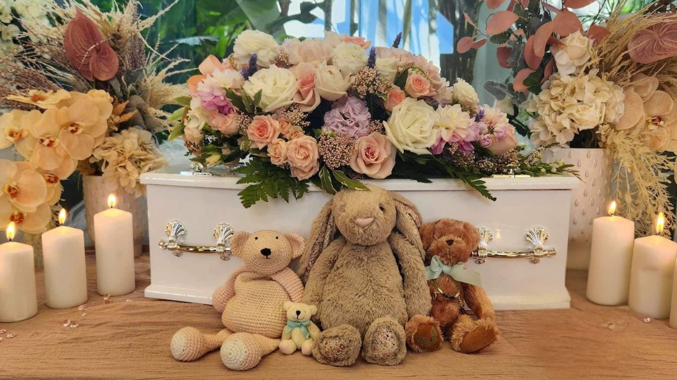 This is an image of a baby coffin with teddy bears around it. 