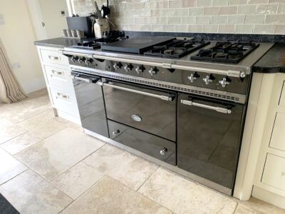 A black stove top oven is sitting on top of a tiled floor in a kitchen.