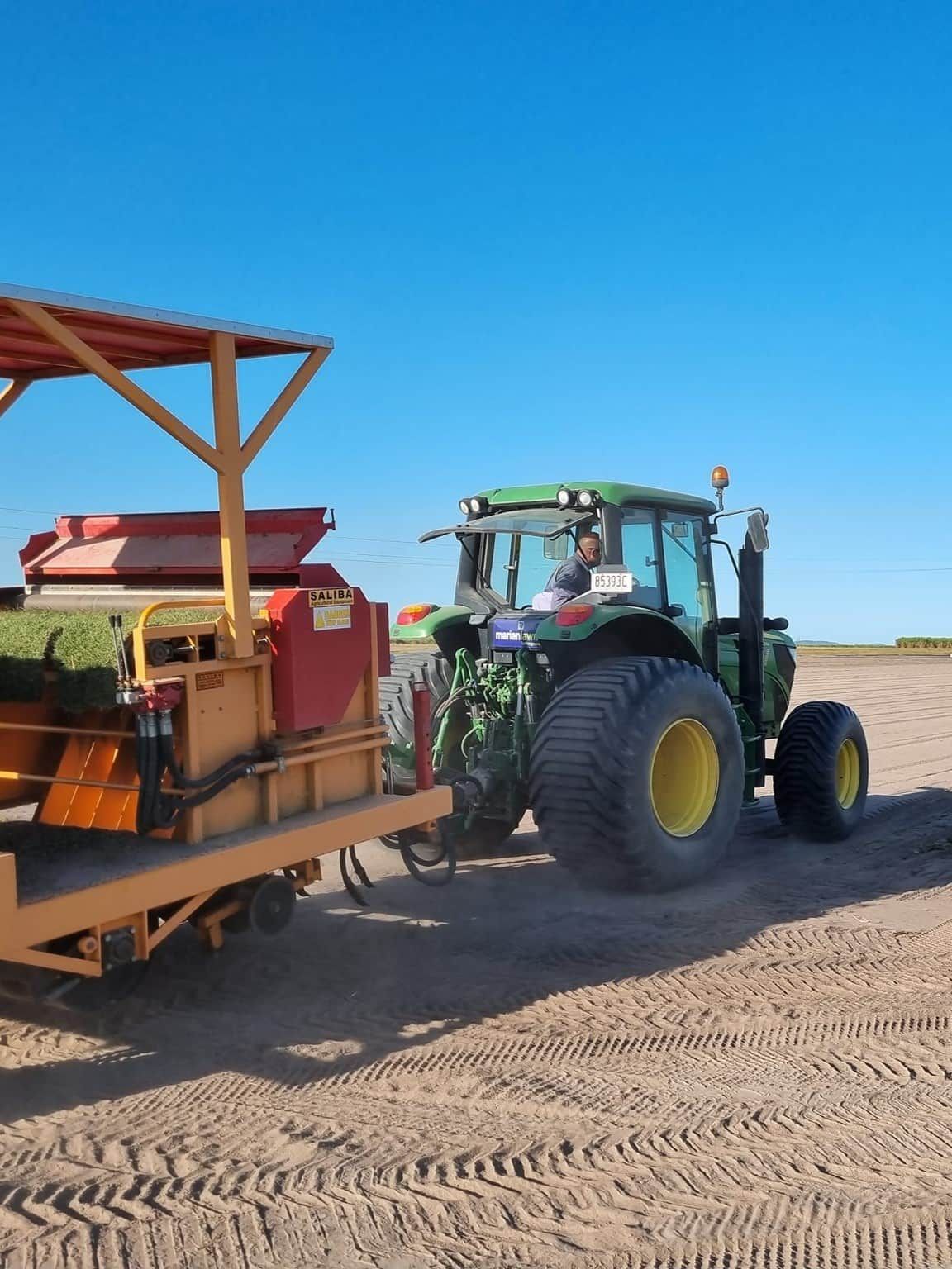 A Man Is Sitting On A Green Tractor In A Field — Marian Lawns In Proserpine, QLD