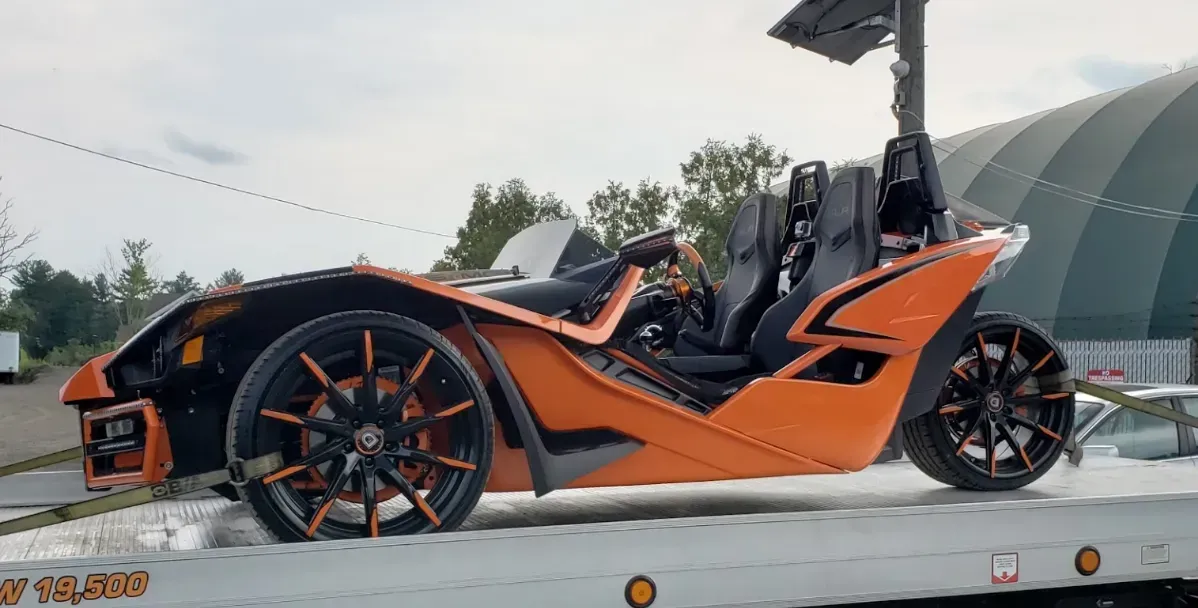 A slingshot is sitting on top of a tow truck.
