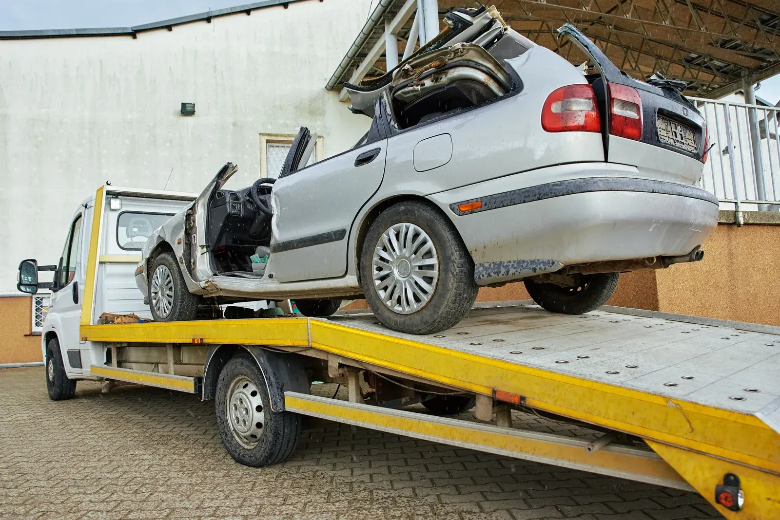 A wrecked car is being towed by a tow truck.