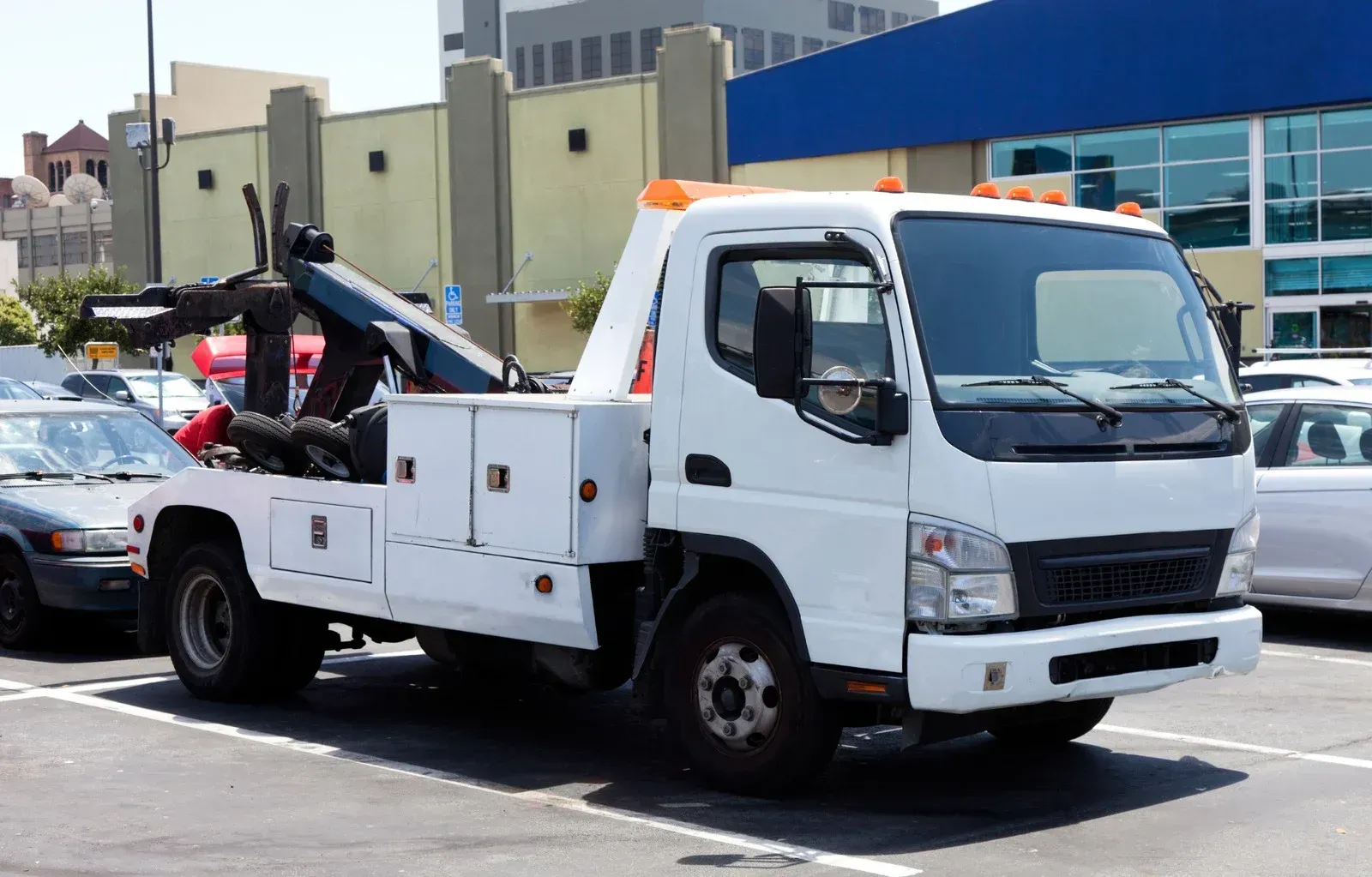 White tow truck parked in a lot with a building in the background.