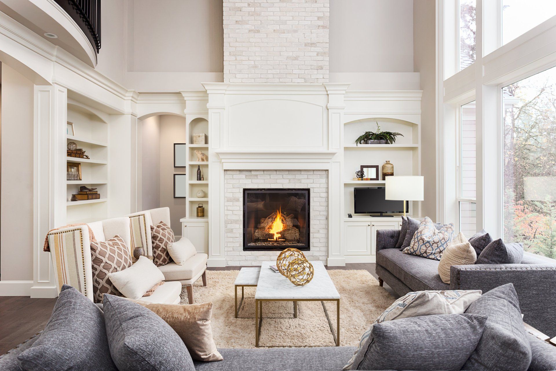 Inviting living room in a new luxury home, featuring a cozy fireplace with a roaring fire, bathed in warm, soft lighting.