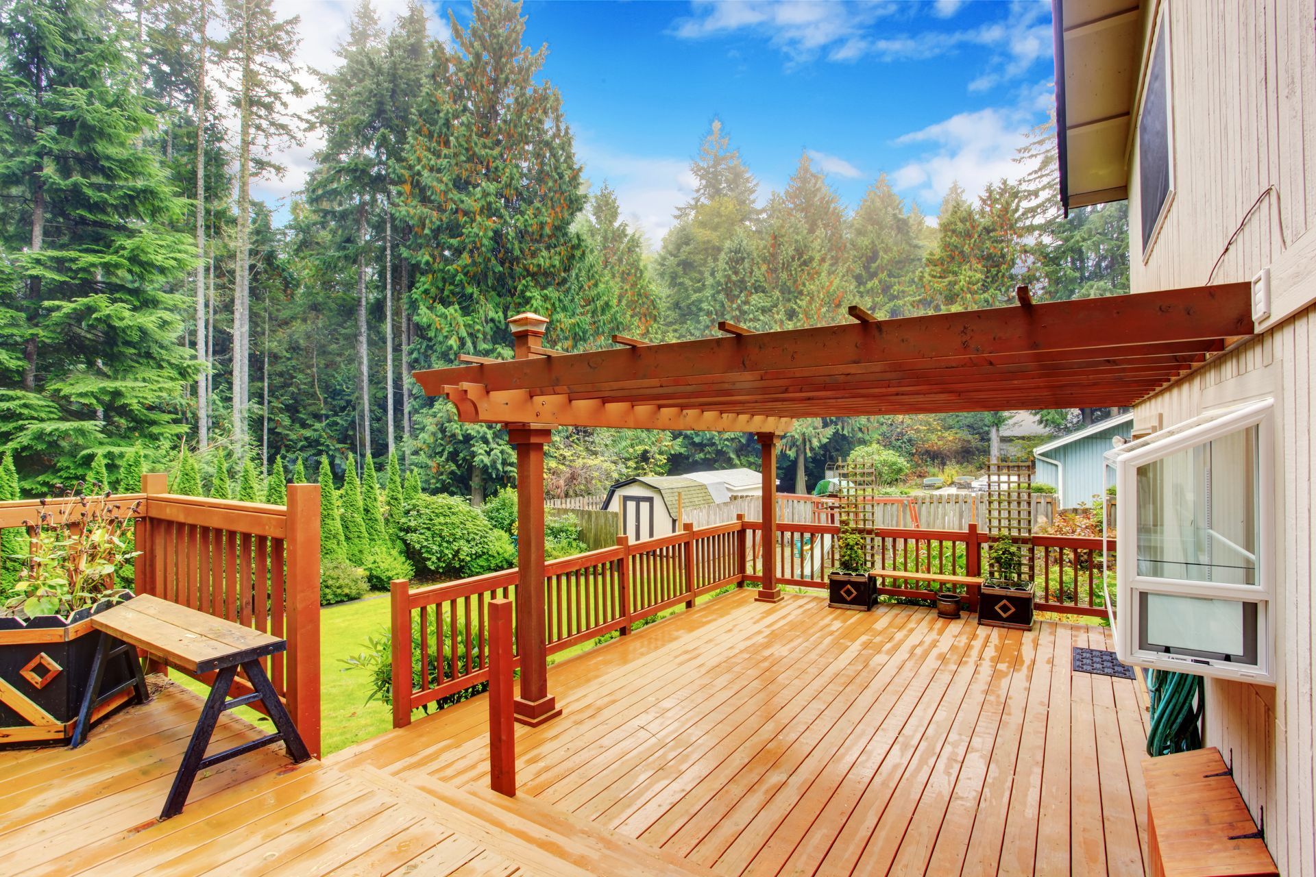 A wooden walkout deck with an attached pergola providing shade and relaxation space.