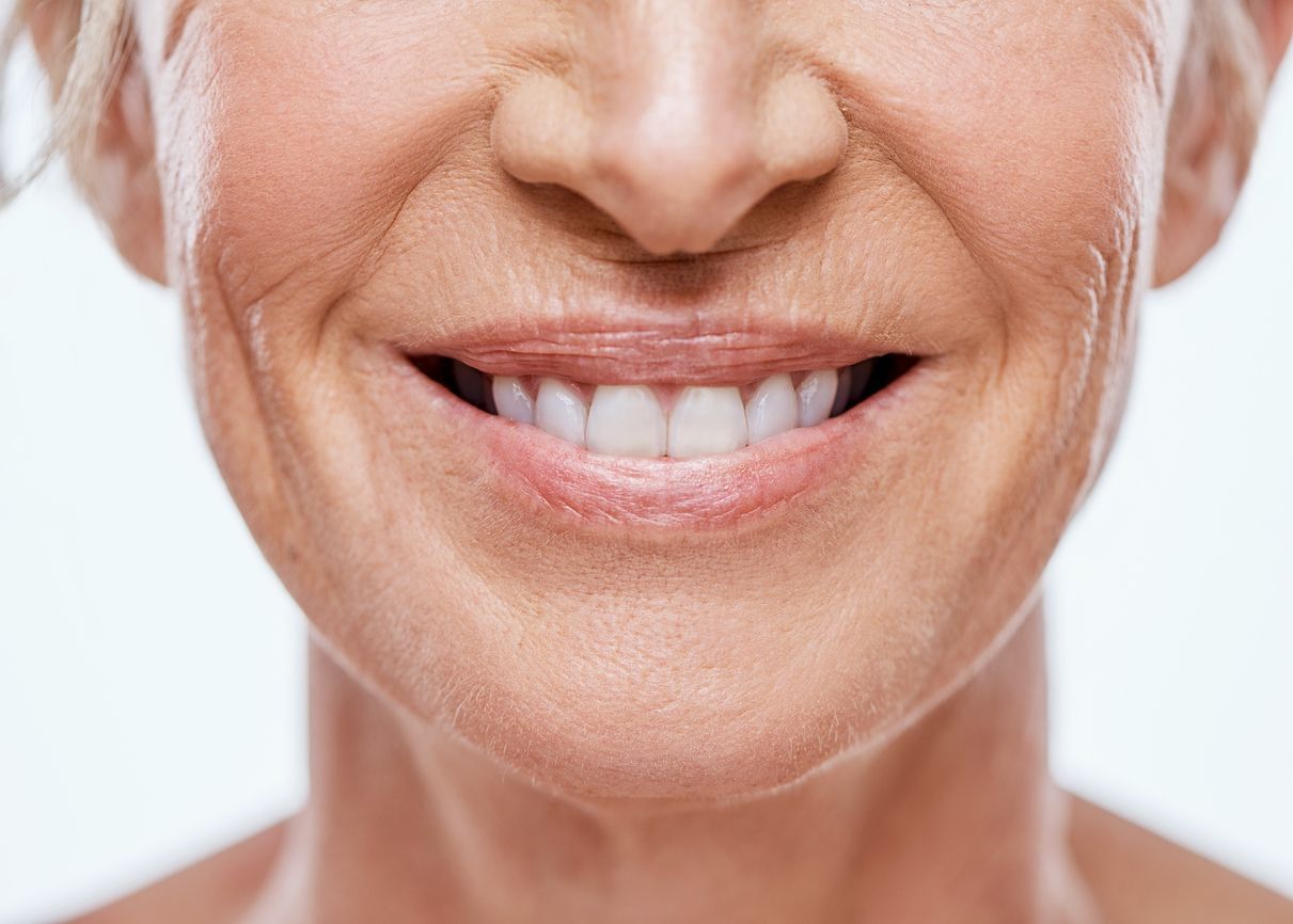 Close-up of a smiling mouth with visible wrinkles and white teeth.