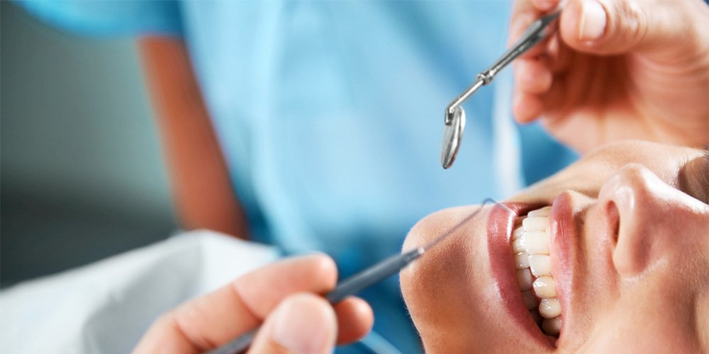 Dentist examining a patient's teeth with a mirror and probe.