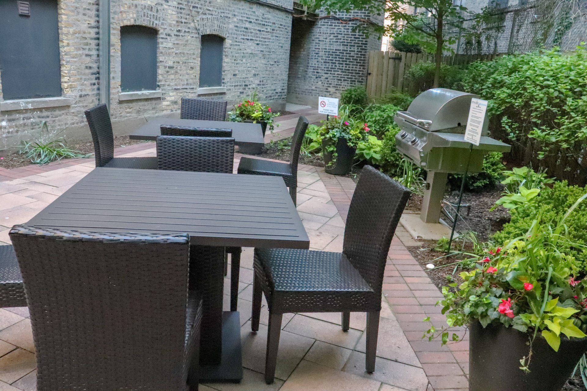 Apartment patio with tables and chairs and a grill at Reside at 849.