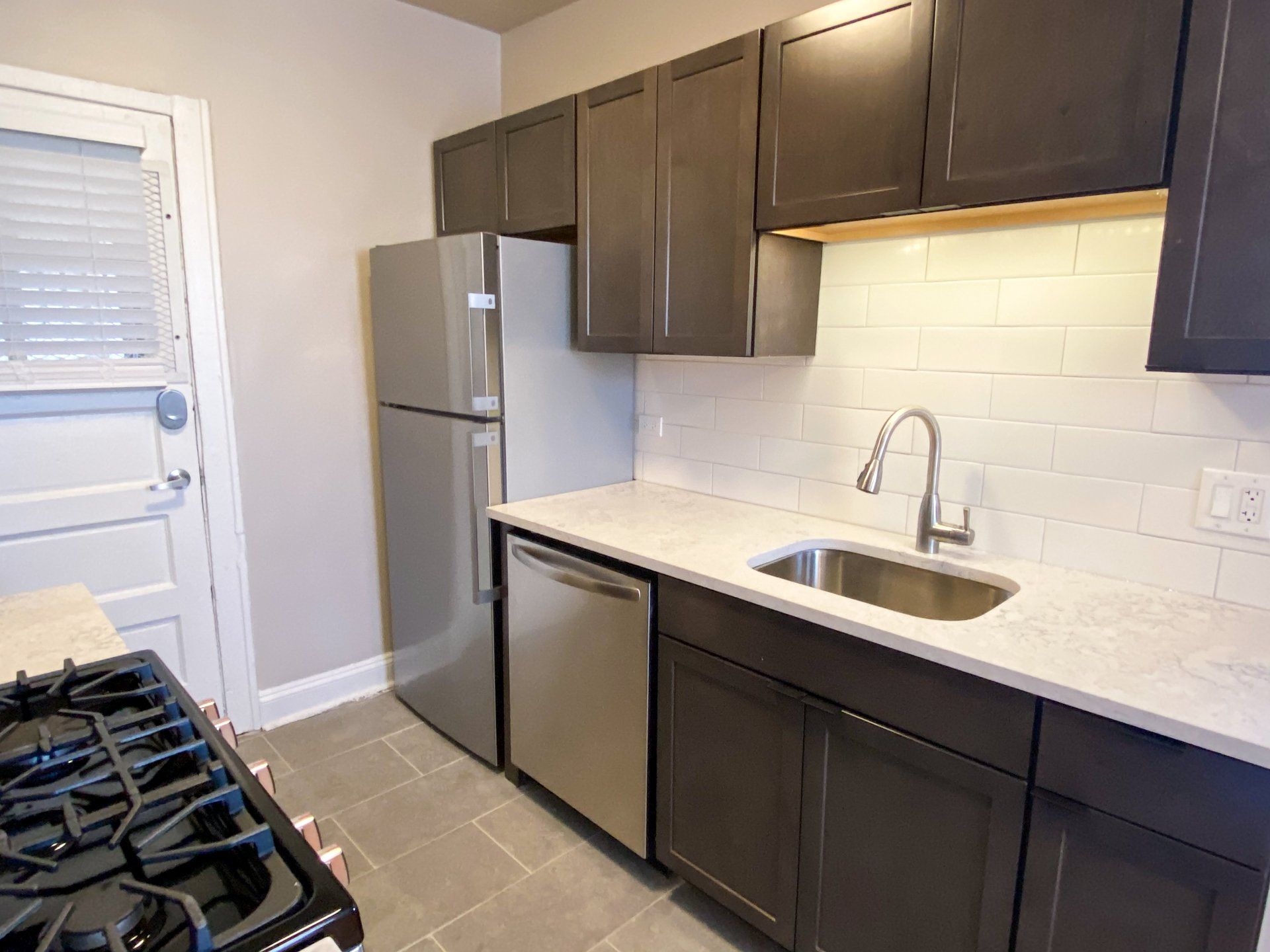 A modern apartment kitchen with a stove, refrigerator, sink, and dishwasher at Reside at 849.