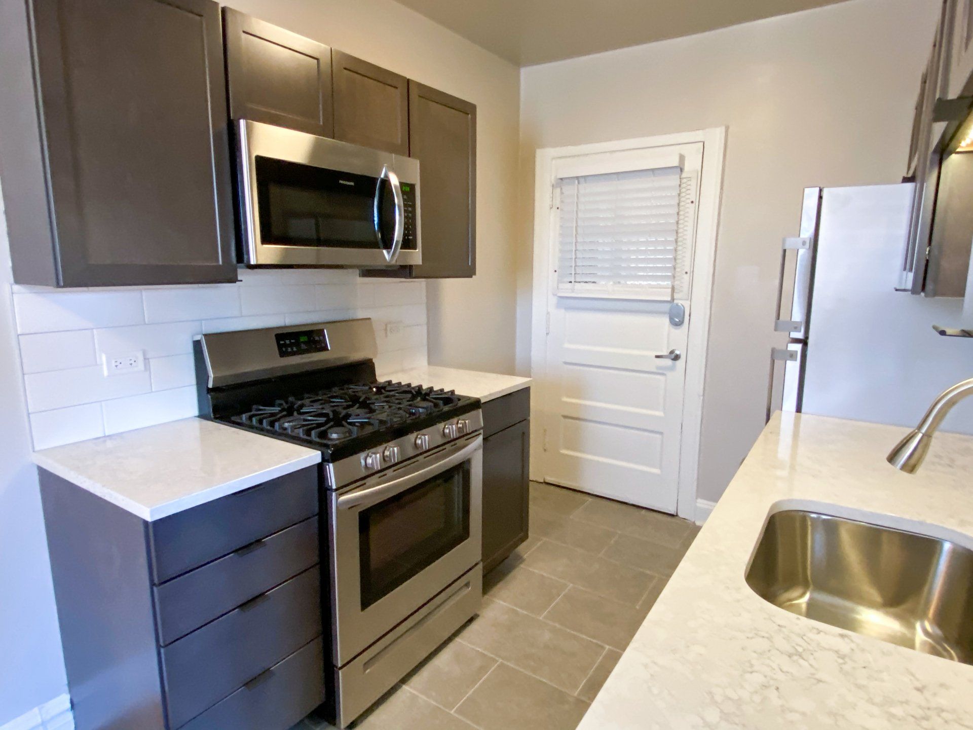 Modern kitchen with stainless steel appliances and a sink at Reside at 849.