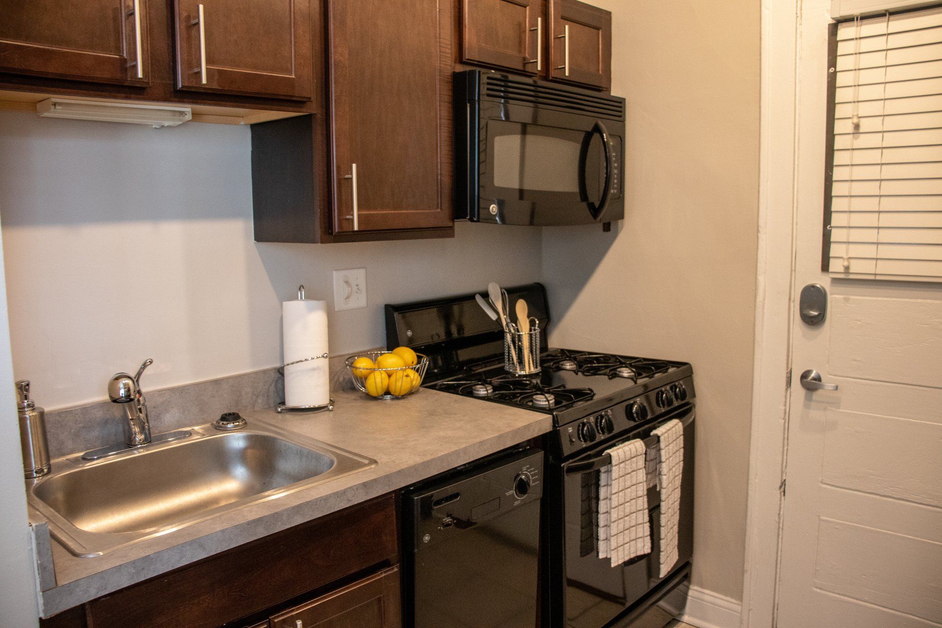 Apartment kitchen with a sink, stove, microwave, and cabinets at Reside at 849.