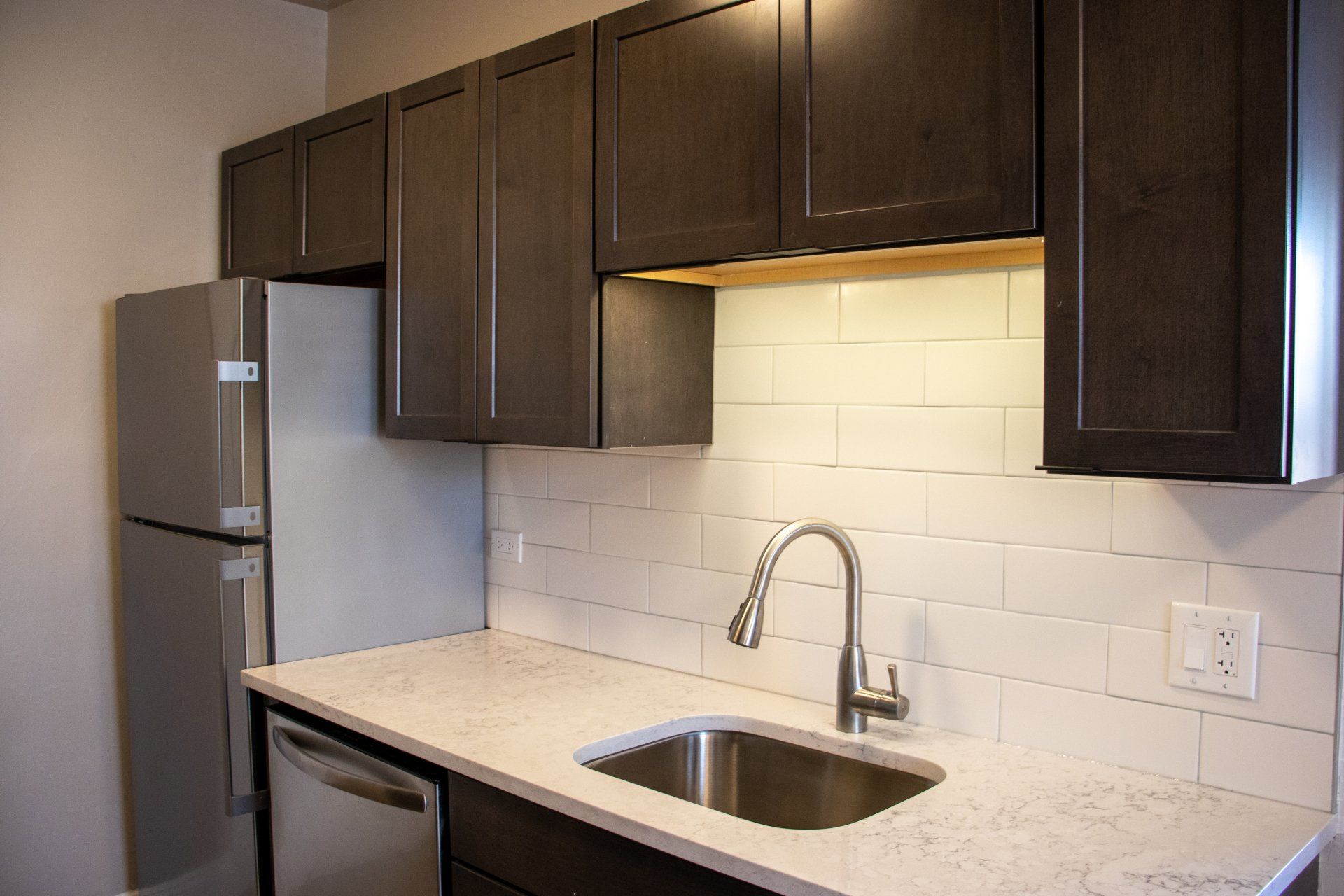 A kitchen with a sink, refrigerator, and dishwasher at Reside at 849.