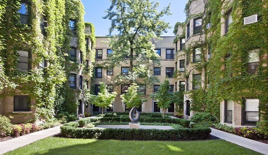 Apartment building with a lush green courtyard in front of it at Reside at 849.