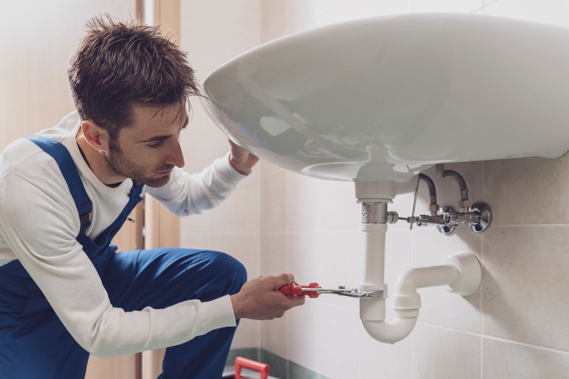 Professional plumber installing or fixing a sink at home.