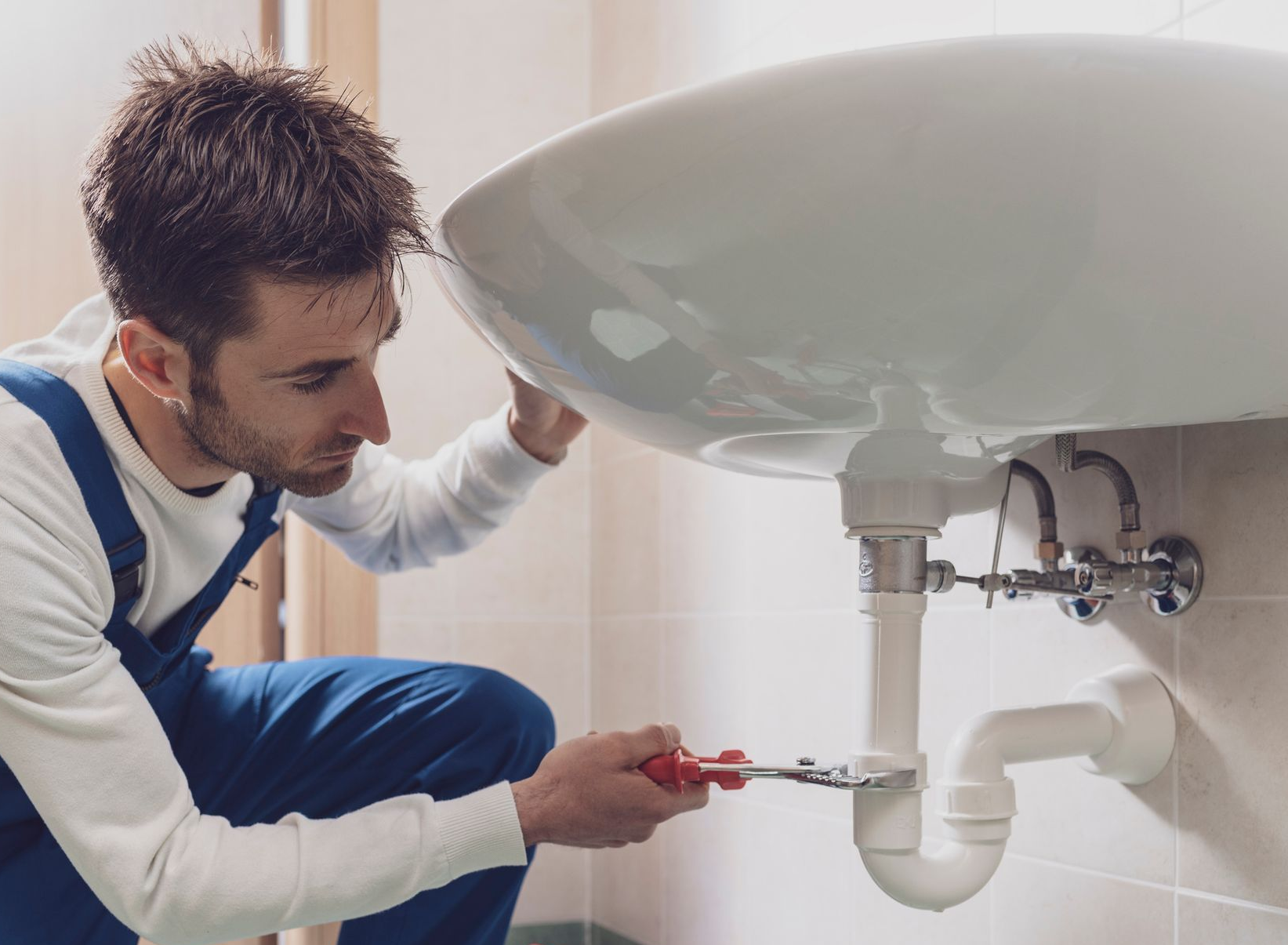 Professional plumber installing or fixing a sink at home.