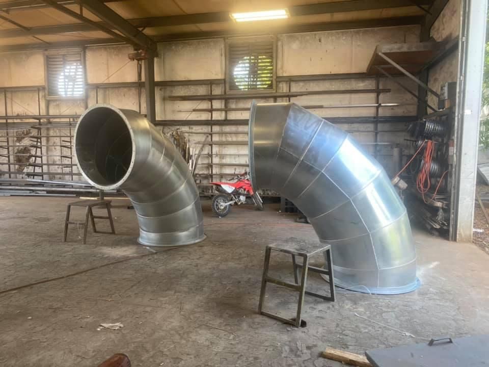 two metal pipes are sitting on the floor in a building .