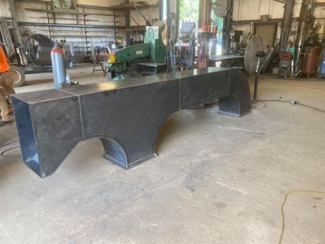 a large piece of metal is sitting on the floor in a factory .