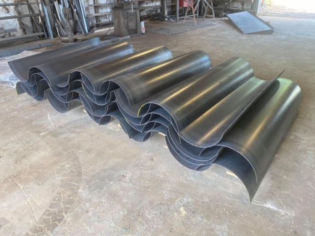 a bunch of metal pipes are stacked on top of each other on the floor .