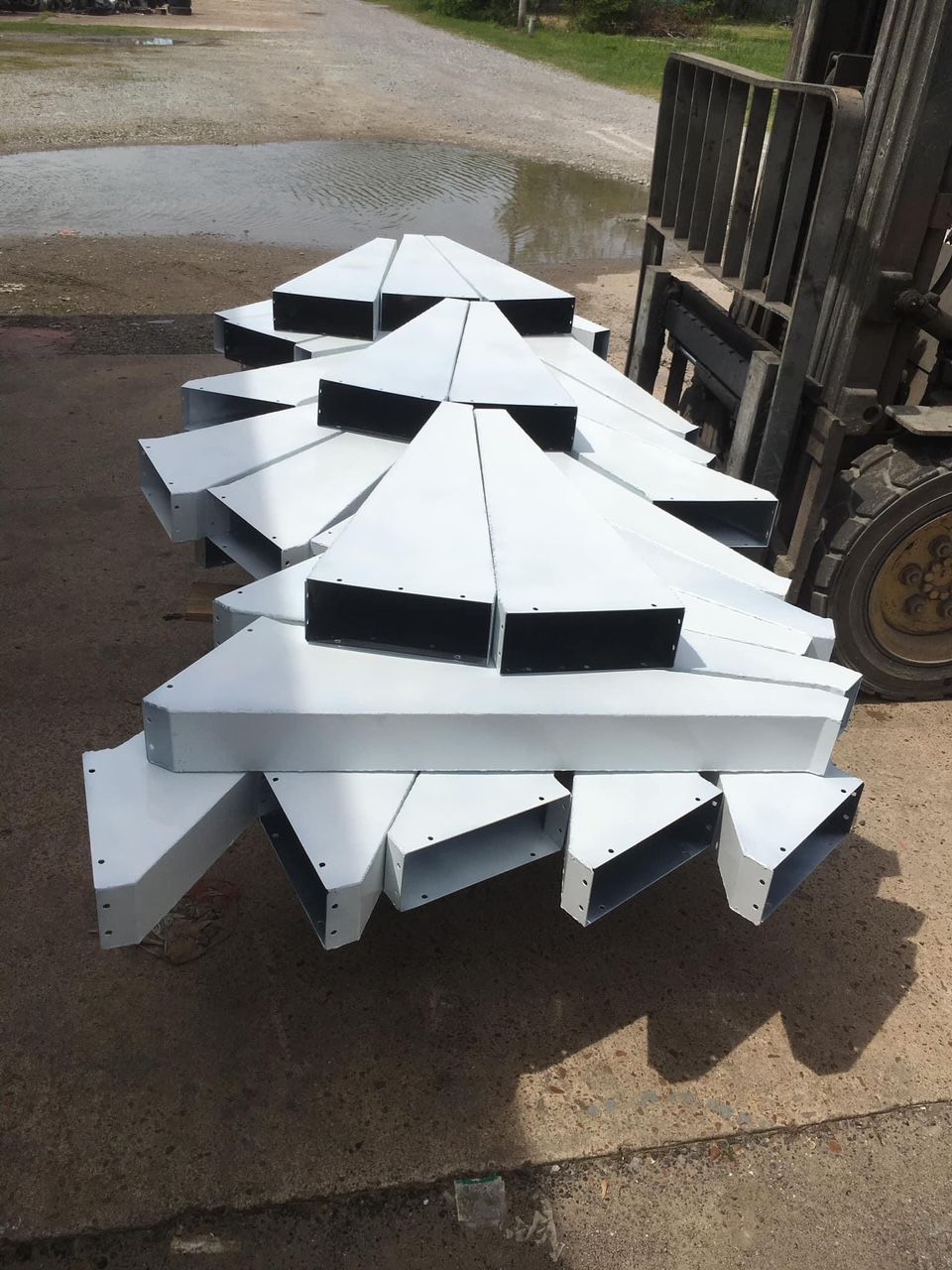 a forklift is carrying a stack of white metal pieces