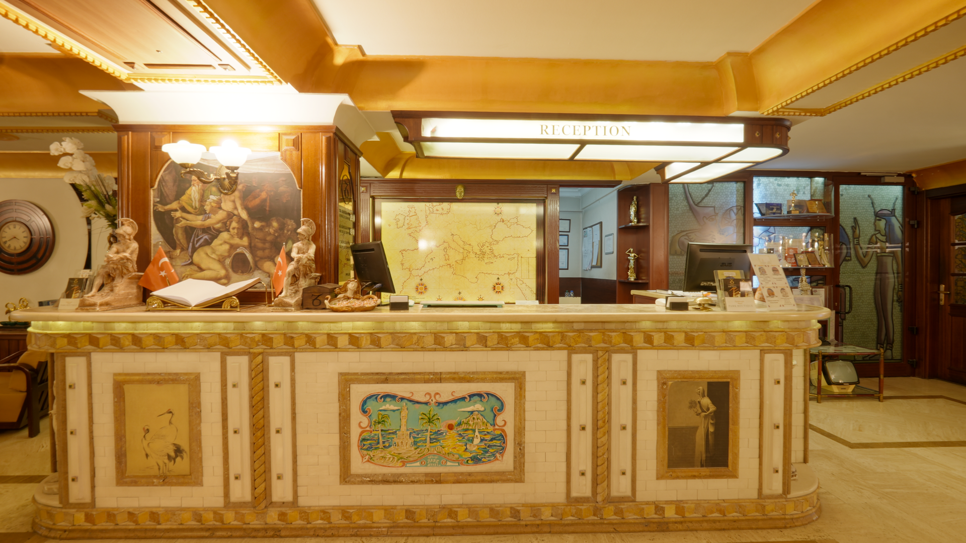 İzmir Park Hotel reception desk with decorative gold trim and tiled panels, featuring a lit signage sign above the counter.
