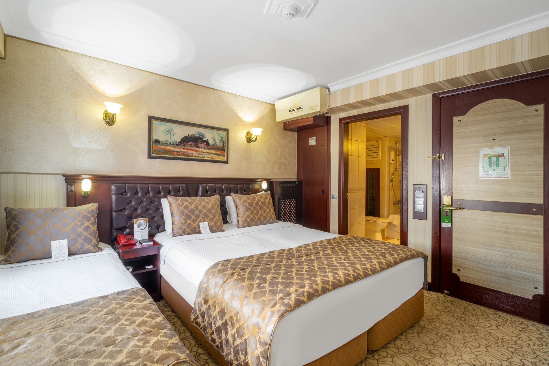 Oğlakçıoğlu Park Hotel Izmir A hotel room with two beds, featuring a brown patterned bed runner, a framed landscape painting.