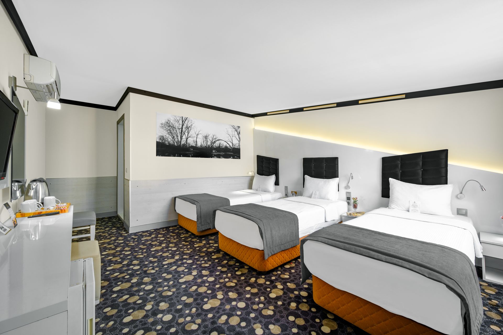 İzmir Park Hotel's room featuring three single beds with white linens, grey throws, and a patterned carpet.