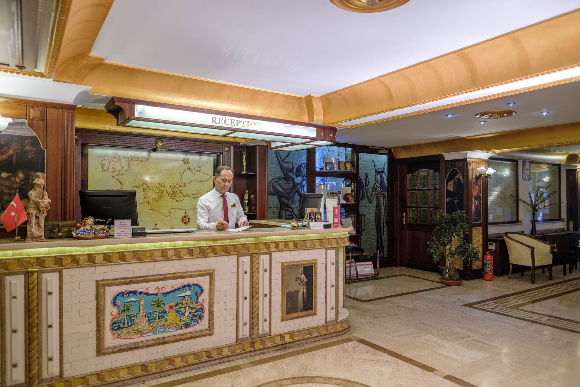 A reception desk in Park Hotel lobby with a staff member working behind it, featuring patterned tile decor and warm lighting.