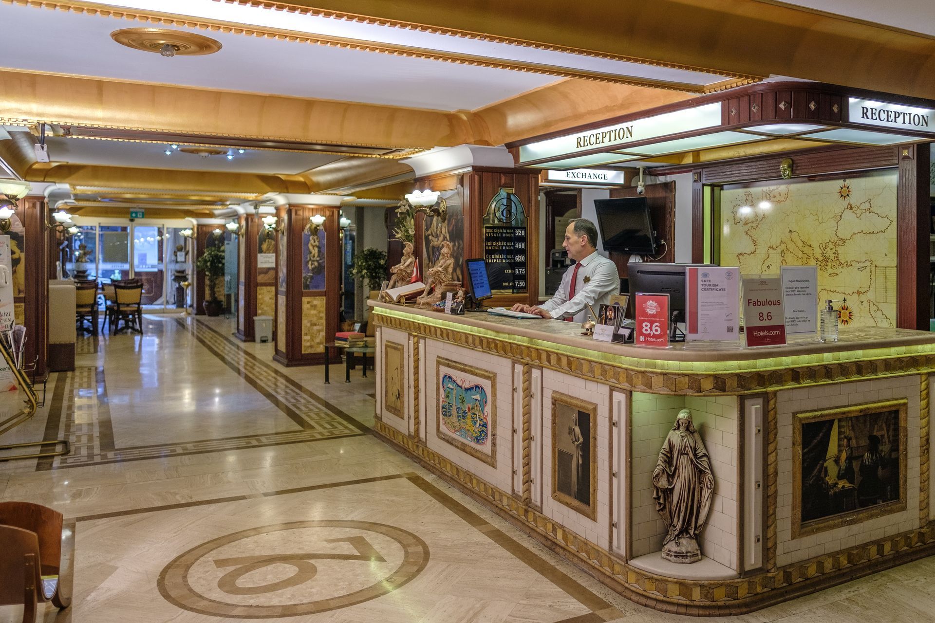 Oğlakçıoğlu Park Hotel lobby with a decorative reception desk, marble floors, and an employee standing behind the counter.