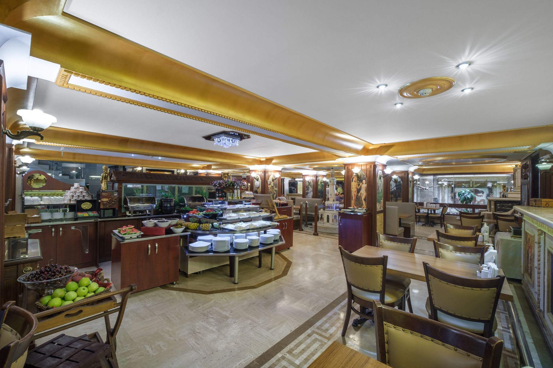 İzmir Park Hotel's buffet dining area with tables, chairs, and food stations under decorative gold-trimmed ceilings.