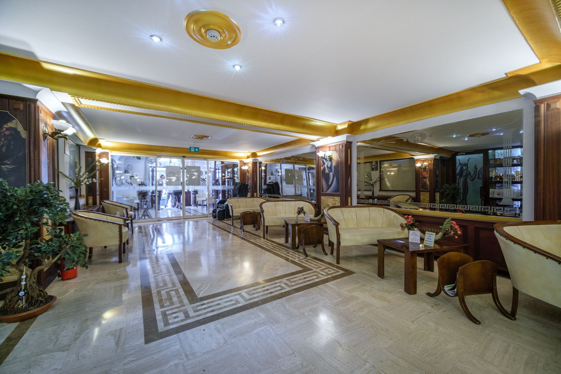 Oğlakçıoğlu İzmir Park Hotel lobby with beige lounge chairs, marble flooring, and gold-trimmed ceilings.