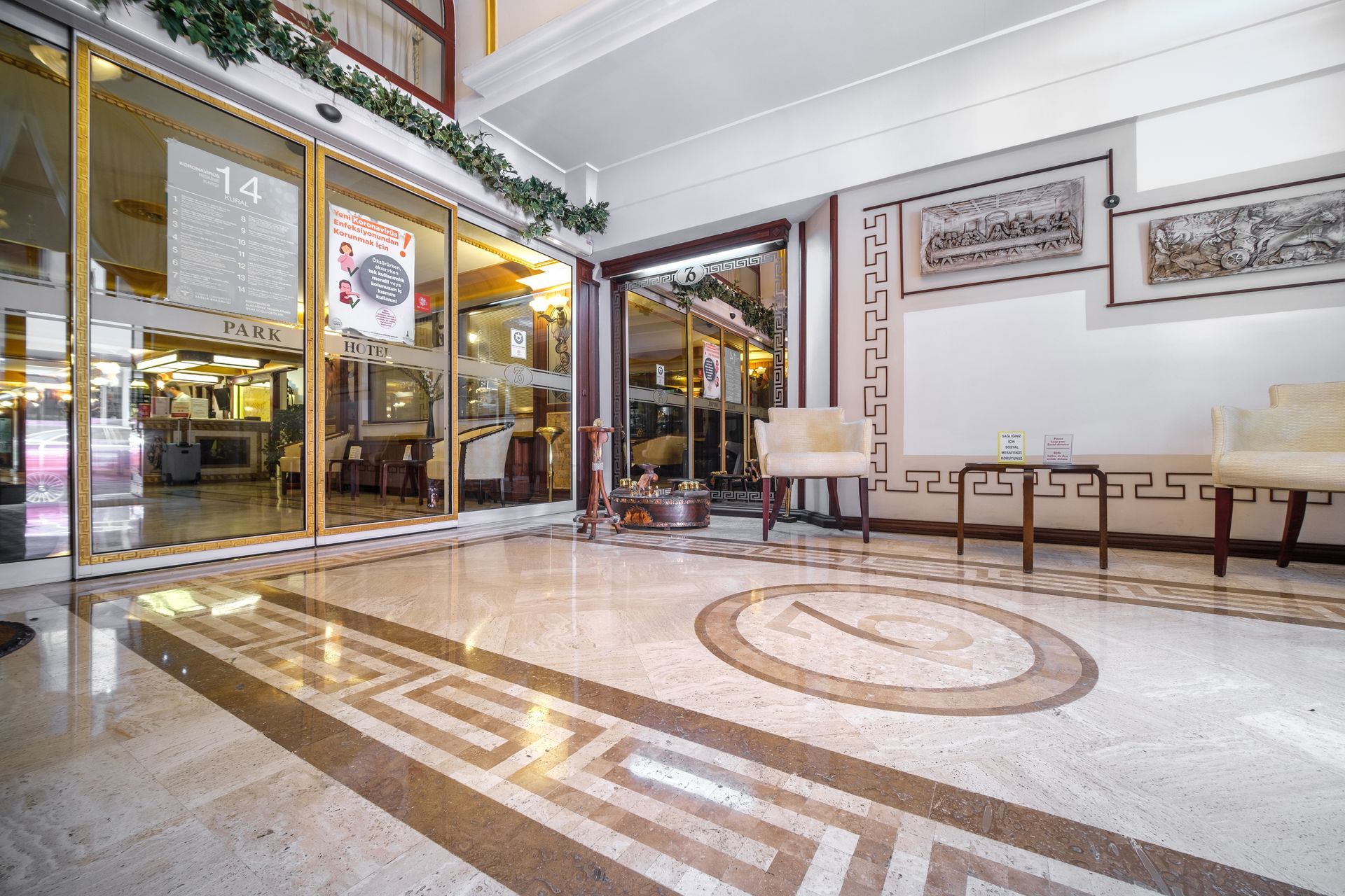 İzmir Park Hotel lobby entrance with polished stone floors featuring Greek key patterns, glass doors, and seating areas.