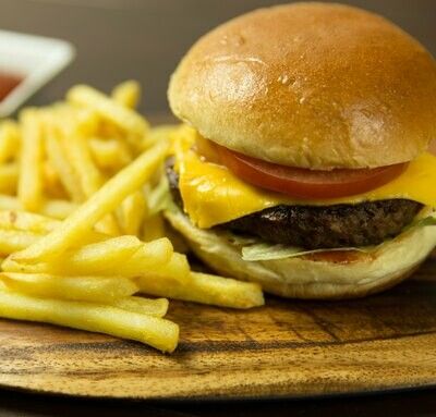 A hamburger and french fries on a wooden cutting board