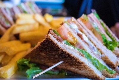 A close up of a club sandwich and french fries on a plate.