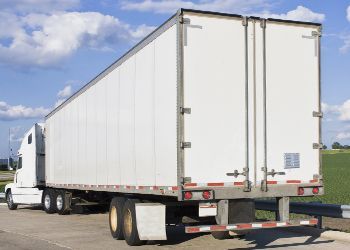 A white semi truck is parked on the side of the road.