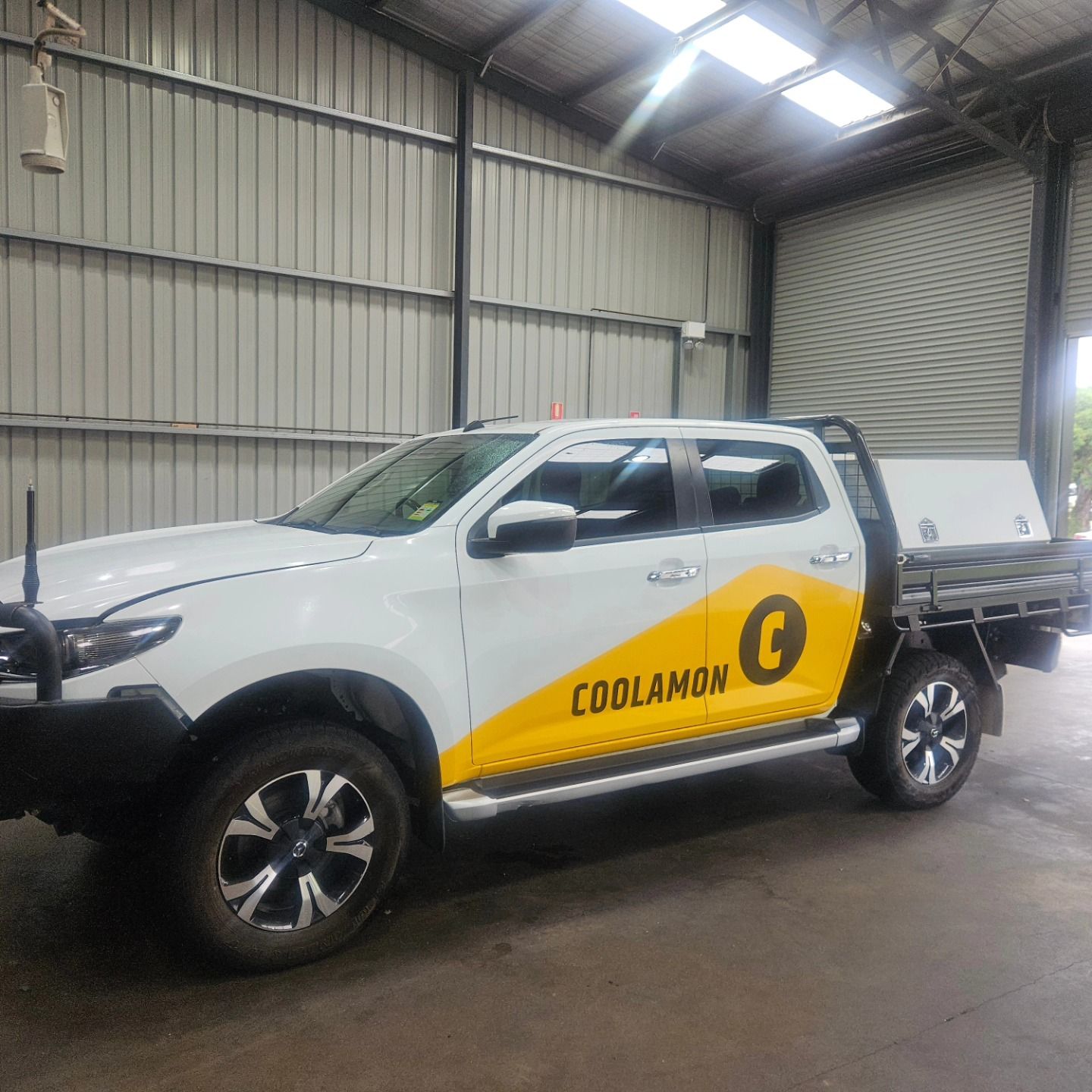 White Coolamon ute parked inside a warehouse, with yellow logo branding on the door and tray. — On Point Detailing Wagga in East Wagga Wagga, NSW