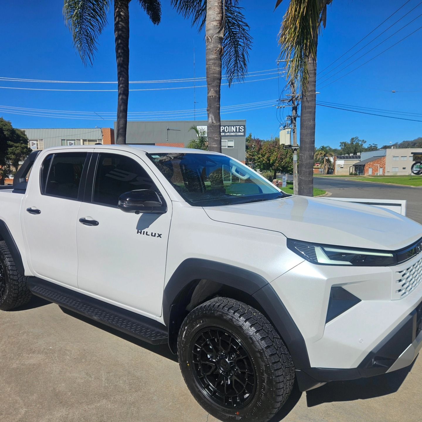 White Toyota Tacoma pickup with black off-road wheels parked outdoors under a clear blue sky. — On Point Detailing Wagga in East Wagga Wagga, NSW