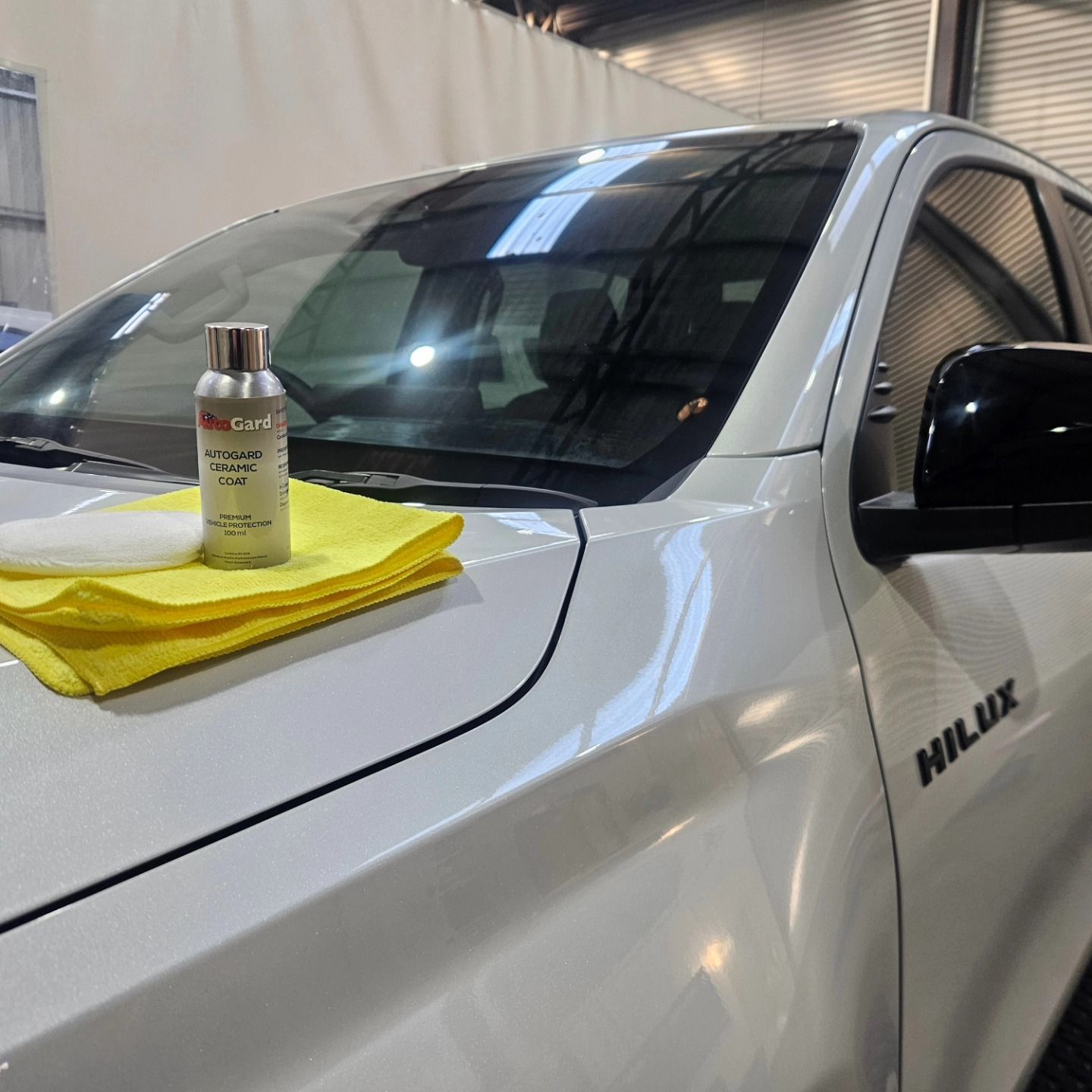 White pickup truck hood with a bottle and yellow microfiber cloth in a garage detailing bay — On Point Detailing Wagga in East Wagga Wagga, NSW