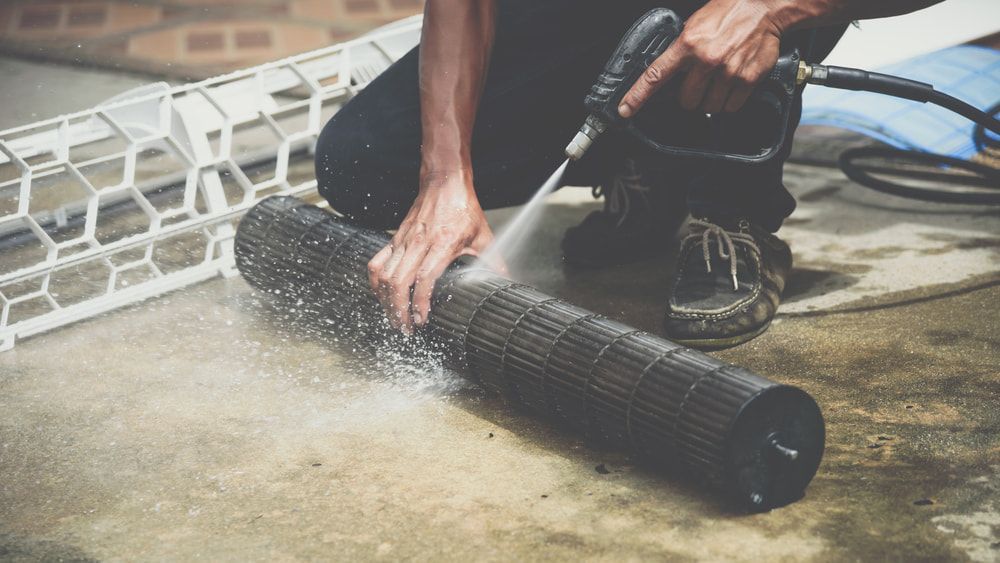 Person Cleaning an Air Conditioner Filter  — Hinterland Air Conditioning Sunshine Coast in Palmwoods, QLD