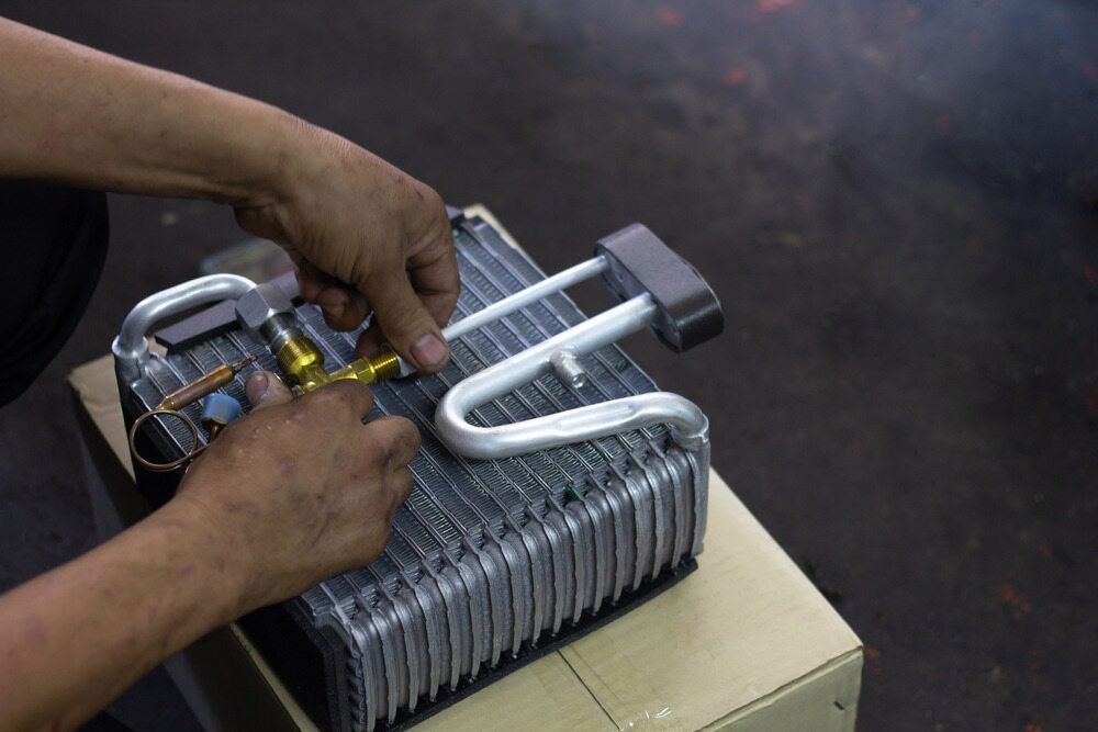 Hands Attaching a Valve to a Ac Evaporator Coil — Hinterland Air Conditioning Sunshine Coast in Mapleton, QLD