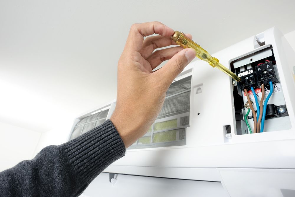 Hand Using a Screwdriver on an Open Air Conditioner — Hinterland Air Conditioning Sunshine Coast in Buderim, QLD