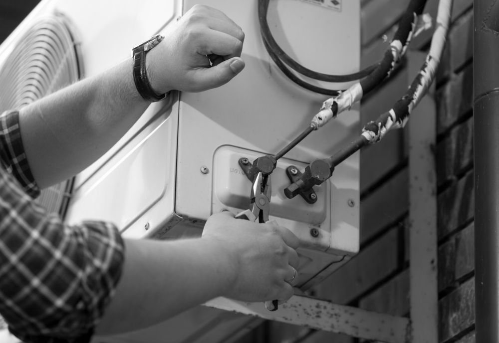 Person Using a Wrench on an Air Conditioner Unit — Hinterland Air Conditioning Sunshine Coast in Yandina, QLD