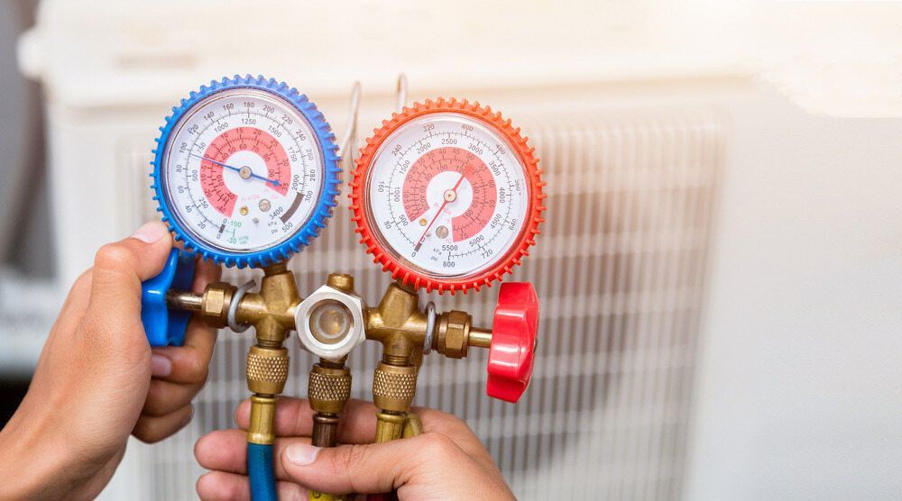 Hands Holding Gauges Connected to an AC Unit — Hinterland Air Conditioning Sunshine Coast in Eudlo, QLD