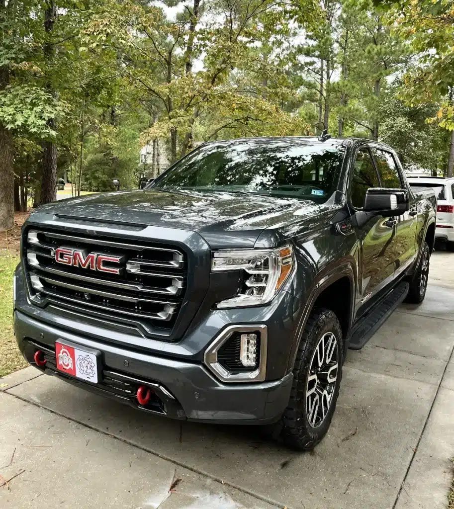 Dark gray GMC pickup truck parked on a tree-lined driveway